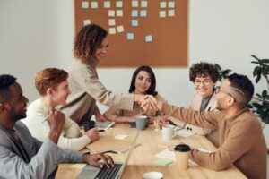 Une équipe diversifiée collaborant lors d'une réunion, mettant en valeur le travail d'équipe et la coopération dans un lieu de travail moderne.