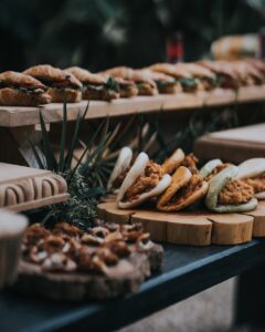 Une variété de sandwichs gastronomiques présentés sur des plateaux en bois rustiques lors d'un événement en plein air.