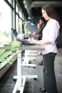 une femme debout à une table utilisant un ordinateur portable