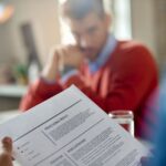 Un candidat tient son CV face à un recruteur. L'image est floue à l'arrière-plan, mettant l'accent sur le document, pour illustrer la création CV.