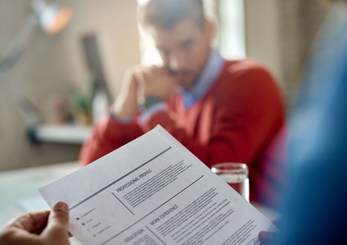 Un candidat tient son CV face à un recruteur. L'image est floue à l'arrière-plan, mettant l'accent sur le document, pour illustrer la création CV.
