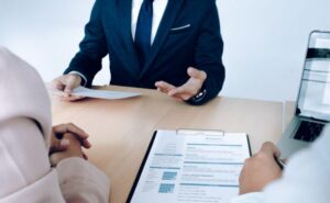Un recruteur discute avec un candidat qui a un CV posé sur la table, illustrant l'importance de la création de CV.