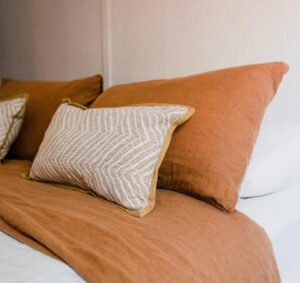 Chambre minimaliste avec coussins beiges et terracotta apportant une ambiance chaleureuse et apaisante.