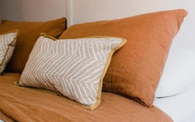 Chambre minimaliste avec coussins beiges et terracotta apportant une ambiance chaleureuse et apaisante.