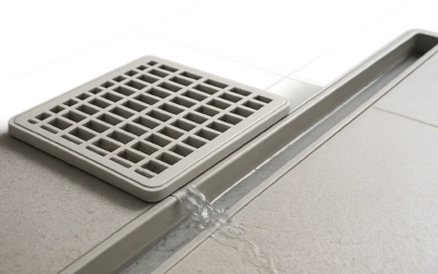 Illustration d’une grille en plastique qui retient les débris avant la canalisation. Une scène claire et moderne pour montrer son rôle ضد bouchons et mauvaises odeurs.
