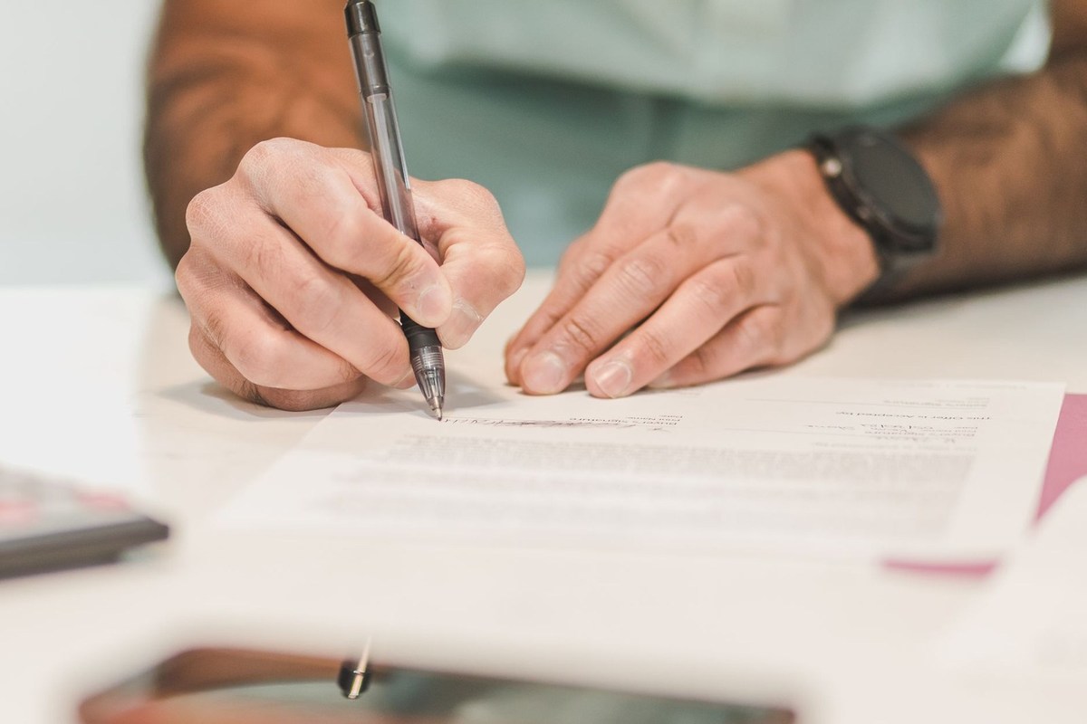 Mains d'une personne écrivant sur un papier avec un stylo noir