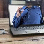 Laptop affichant une personne portant un stéthoscope, avec un stylo et un bloc-notes à proximité