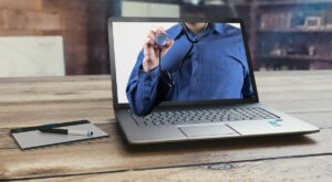 Laptop affichant une personne portant un stéthoscope, avec un stylo et un bloc-notes à proximité