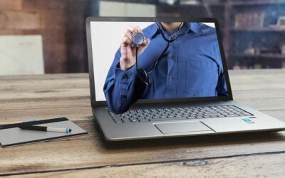Laptop affichant une personne portant un stéthoscope, avec un stylo et un bloc-notes à proximité