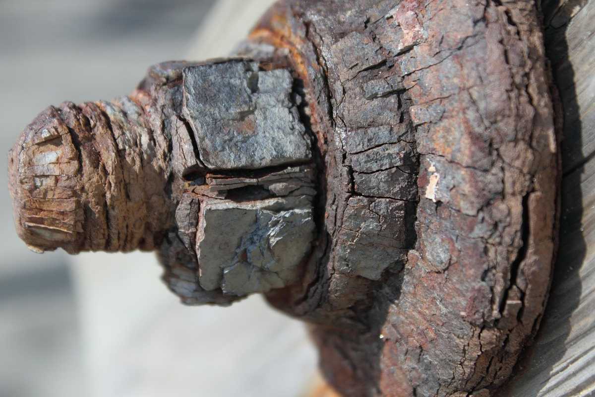 Boulon rouillé et fissuré, fixé sur planche de bois, texture détériorée