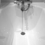 Baignoire blanche avec robinet et tuyau, eau qui coule dans la salle de bain