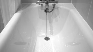 Baignoire blanche avec robinet et tuyau, eau qui coule dans la salle de bain