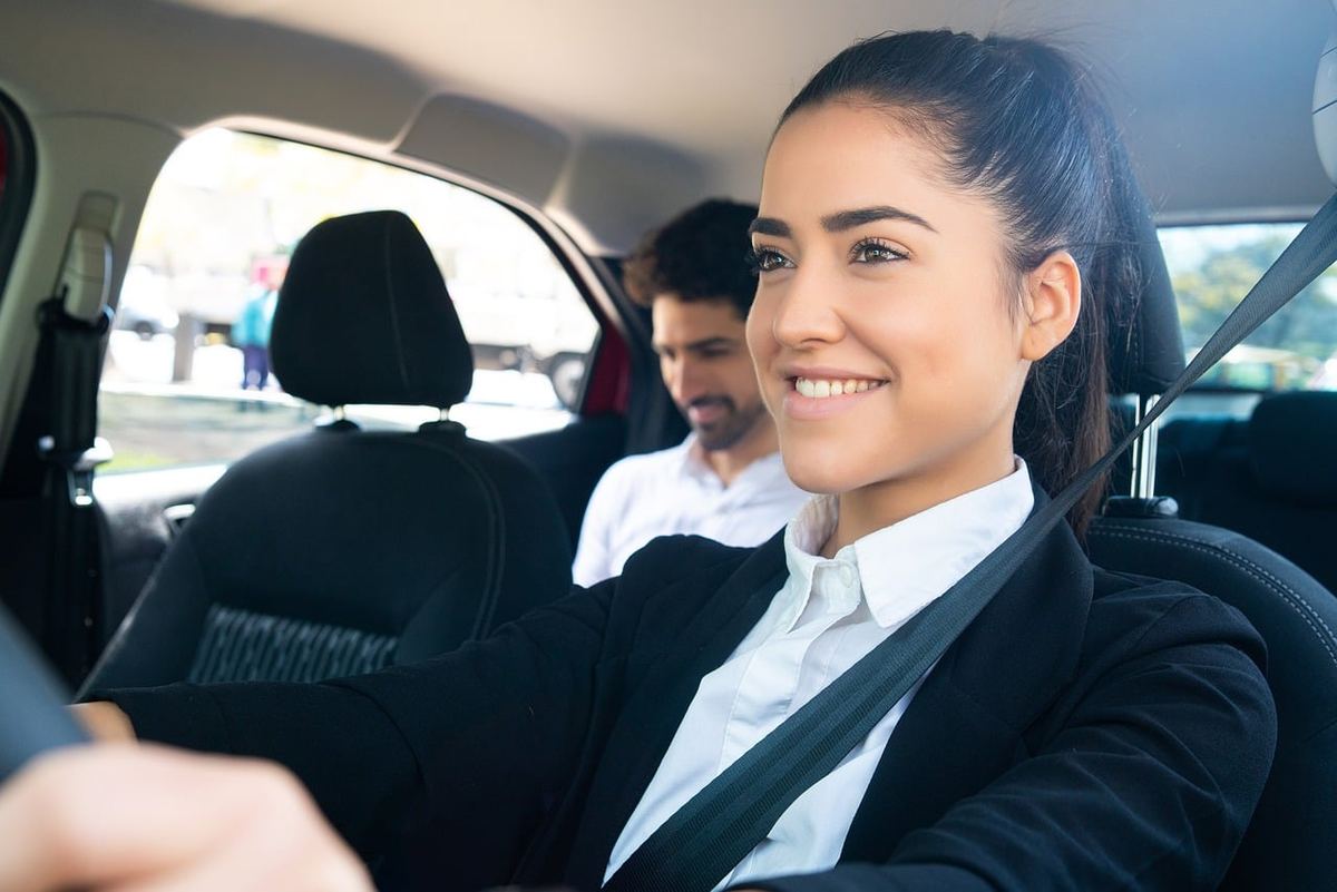 Une femme souriante conduit, passager masculin à l'arrière