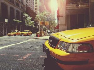 Taxi jaune à l'avant, deux taxis derrière, rue urbaine ensoleillée