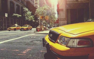 Taxi jaune à l'avant, deux taxis derrière, rue urbaine ensoleillée
