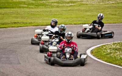 Quatre personnes en karting sur une piste avec un gazon à l'arrière-plan
