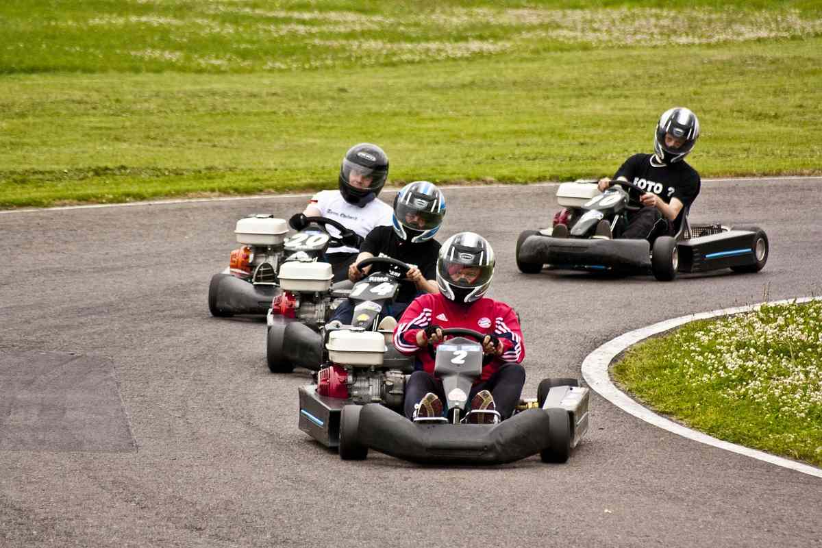 Quatre personnes en karting sur une piste avec un gazon à l'arrière-plan
